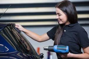 Picture of woman tinting blue car with blue heat gun
